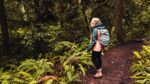 What to wear to the Oregon Coast by season - Woman on a hiking trail wearing raincoat with a backpack