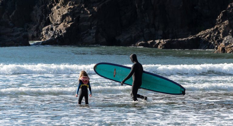 Surfers in the water wearing wetsuits as an example of what to wear in summer at the Oregon Coast