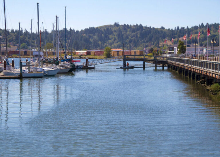 Downtown Coos Bay Boardwalk with boats and flags in Coos Bay, Oregon