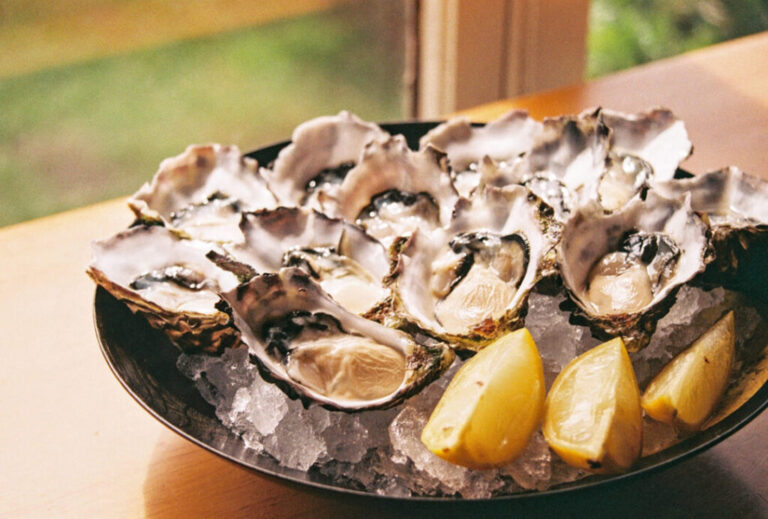A tray of Oregon Coast oysters on ice with lemon wedges