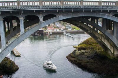 A boat passes under Depoe Bay Bridge, Oregon Coast at the entrance to the smallest harbor in the world