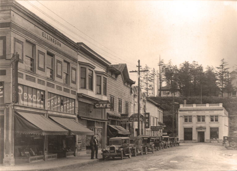 Historical photo of Bandon, Oregon's main street with old cars and shops