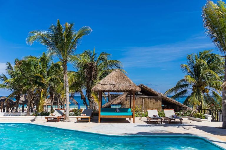 Find your winter sun at Hotel Ojo de Agua in Puerto Morelos, Mexico with a turquoise pool, sun loungers and palm trees