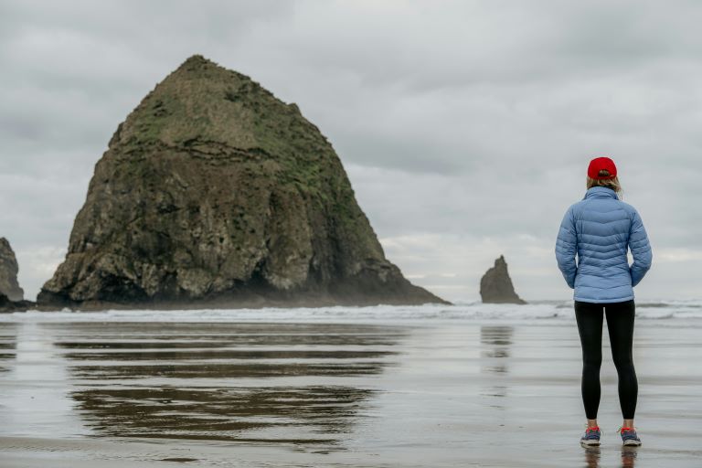 A woman on the beach in front of Haystack Rock, Cannon Beach, Oregon