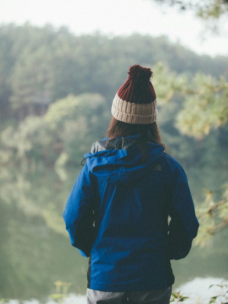A woman in a rain jacket and beanie looks out over the forest as an example of what to wear in spring at the Oregon Coast