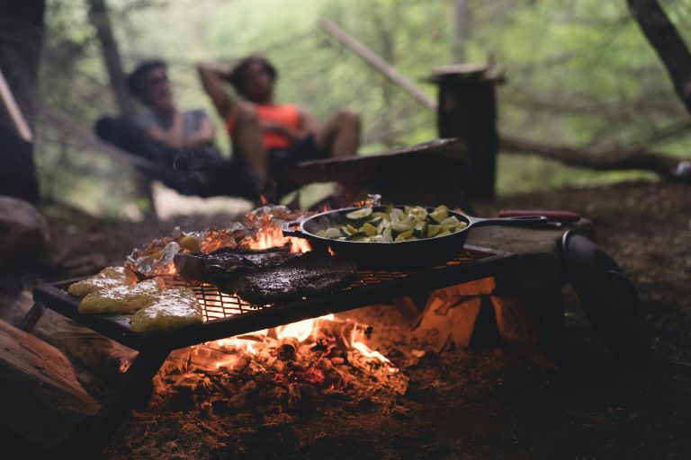 Camping food and cooking equipment being used to grill on a campfire