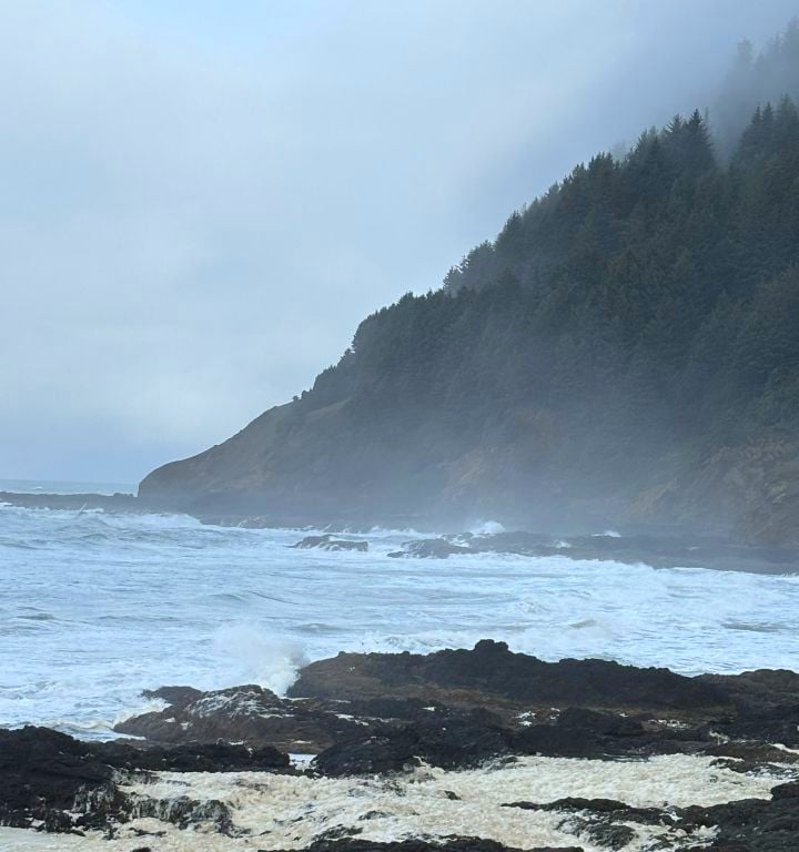 Waves crash on the black rocky shoreline of Cape Perpetua Scenic Area in Yachats, Oregon